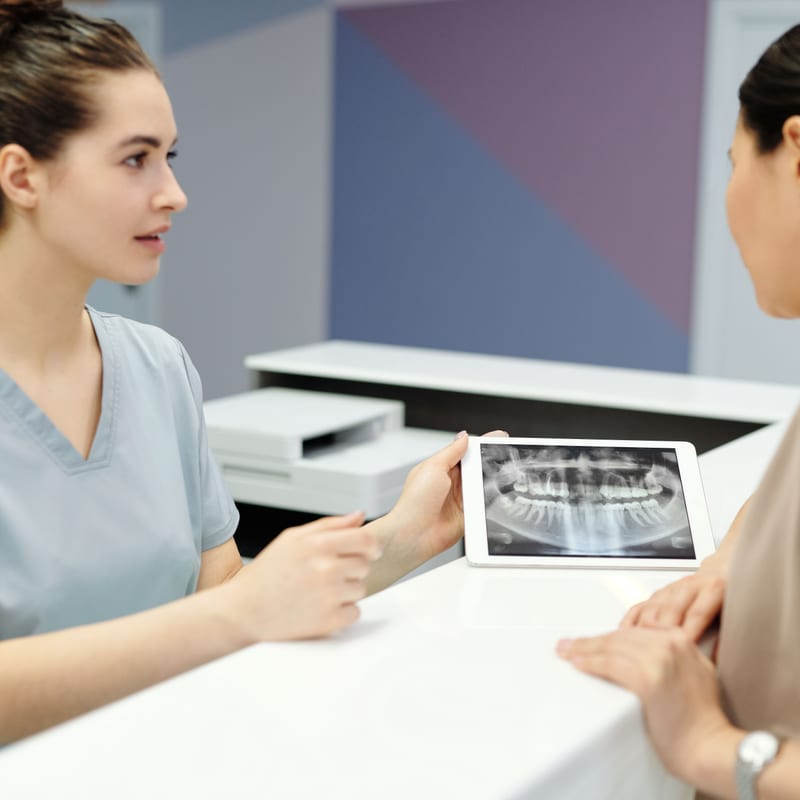 Dental team reviewing a panoramic X-ray on a tablet during a preventive exam